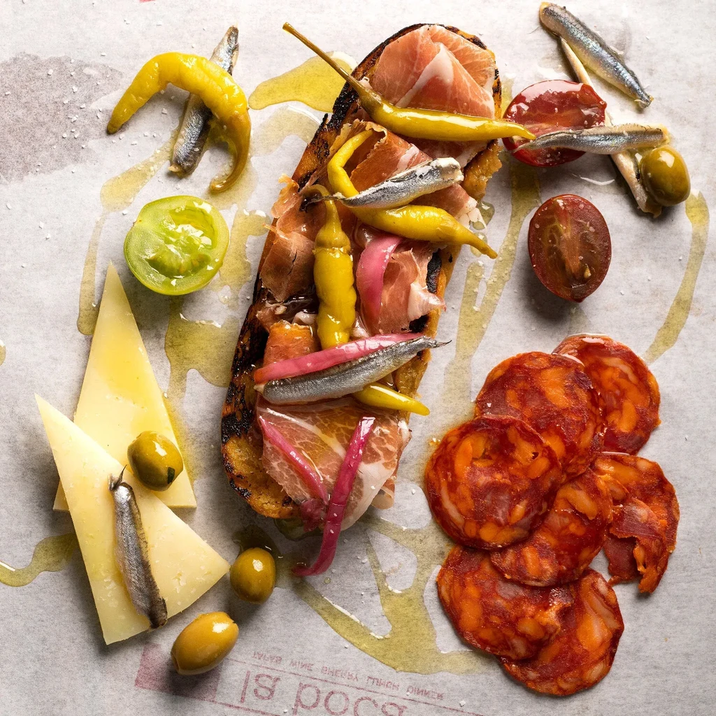 Spanish tapas overhead: grilled bread, ham, cheese, chorizo, olives.