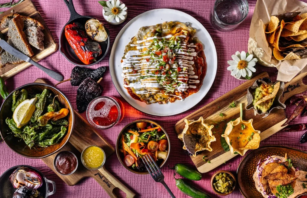 Vibrant overhead shot of diverse Latin American food on pink tablecloth.