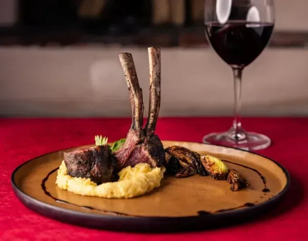 Plated gourmet lamb chops, braised meat, potatoes, and vegetables.