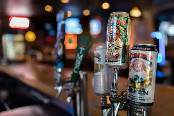 Colorful beer cans with mountain art serving as tap handles.