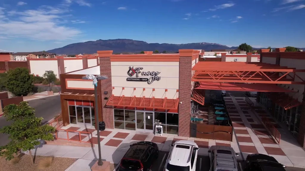 Aerial view of Fuego Rotisserie + Bar, orange and cream building, distant mountains.