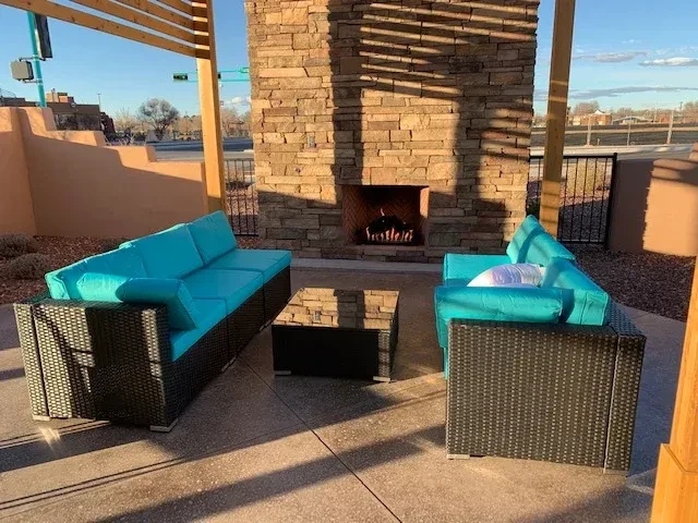 Outdoor patio with wicker sofas, turquoise cushions, stone fireplace, and pergola.