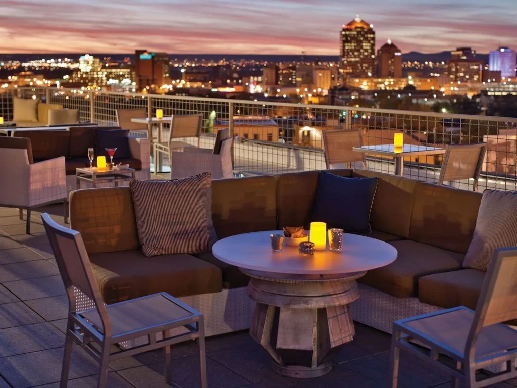Cozy rooftop bar seating at night with glowing candles and city lights.