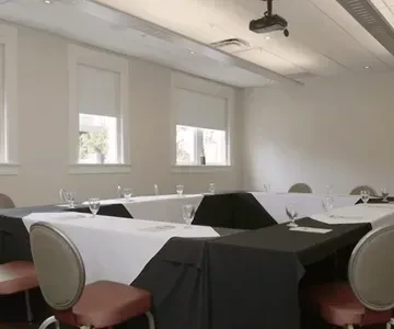 Empty U-shaped meeting room with set tables, chairs, and projector.