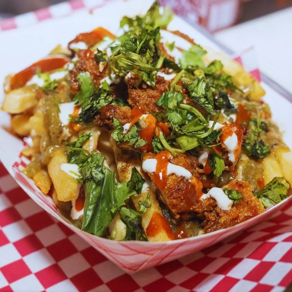 Fries topped with fried protein, various sauces, and cilantro.