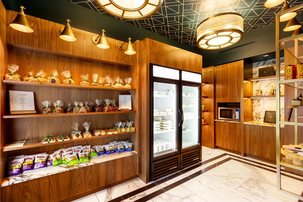 Well-lit, modern deli interior with packaged food shelves and refrigerator.