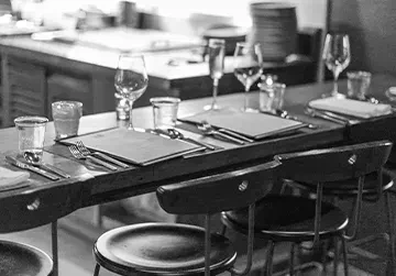 Empty modern restaurant's long wooden dining counter, set for service.