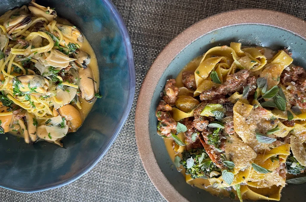 Overhead view of two pasta dishes, mussels and ragu with broccoli.