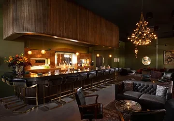 Dark wood bar and leather lounge in a dimly lit interior.