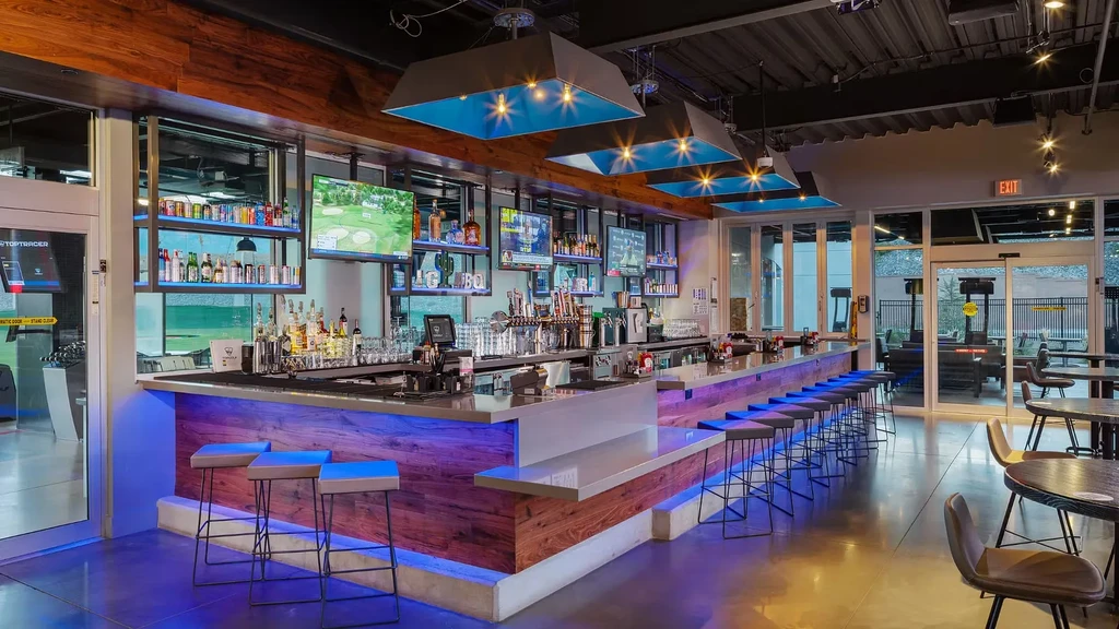 Modern bar with blue LED lighting in a golf entertainment venue.