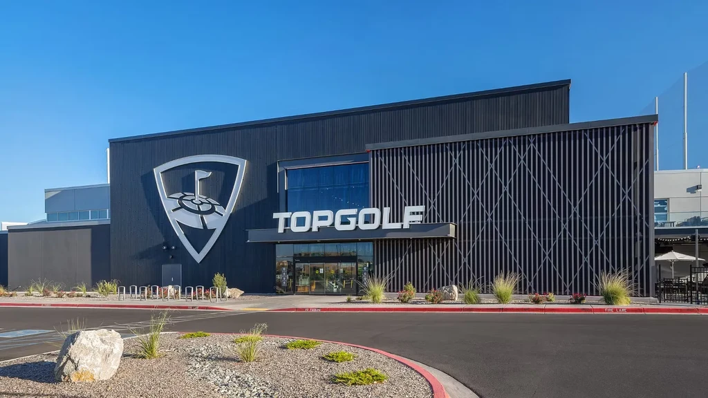 Modern Topgolf building exterior with prominent logo under blue sky.