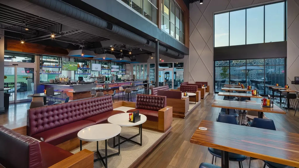 Empty modern restaurant interior with bar, booths, and outdoor views.