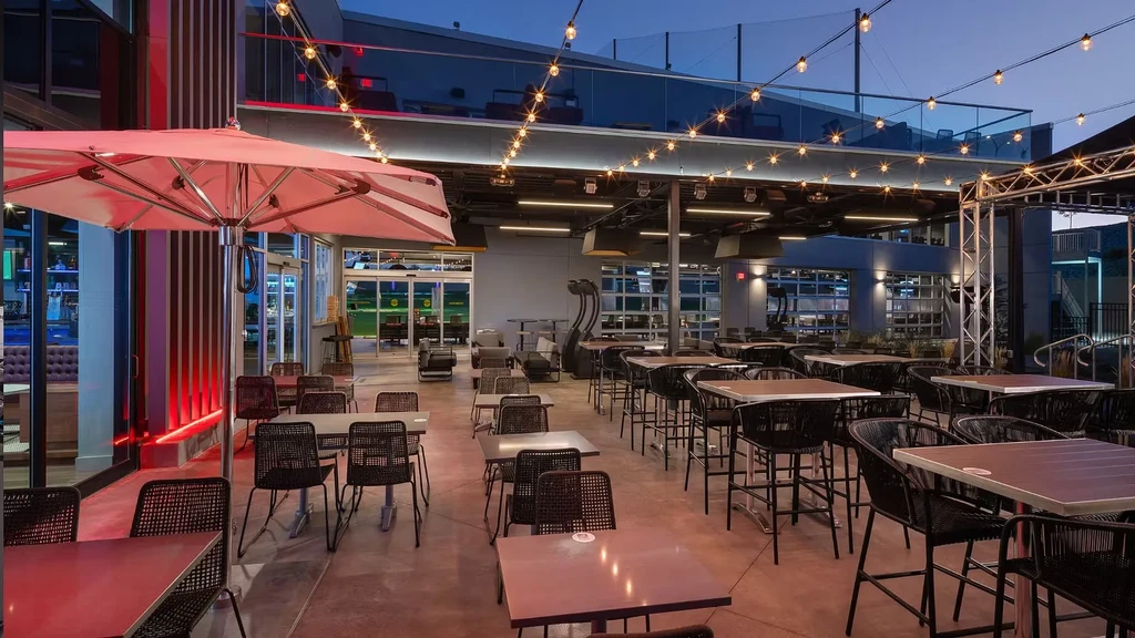 Modern outdoor entertainment patio at night with seating and string lights.