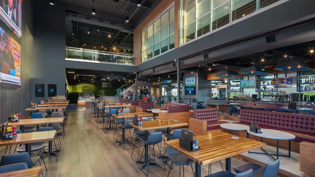 Modern, empty sports bar interior with high ceilings and large screens.