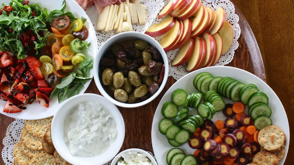 Elaborate top-down food spread with fresh produce, meats, and cheeses.