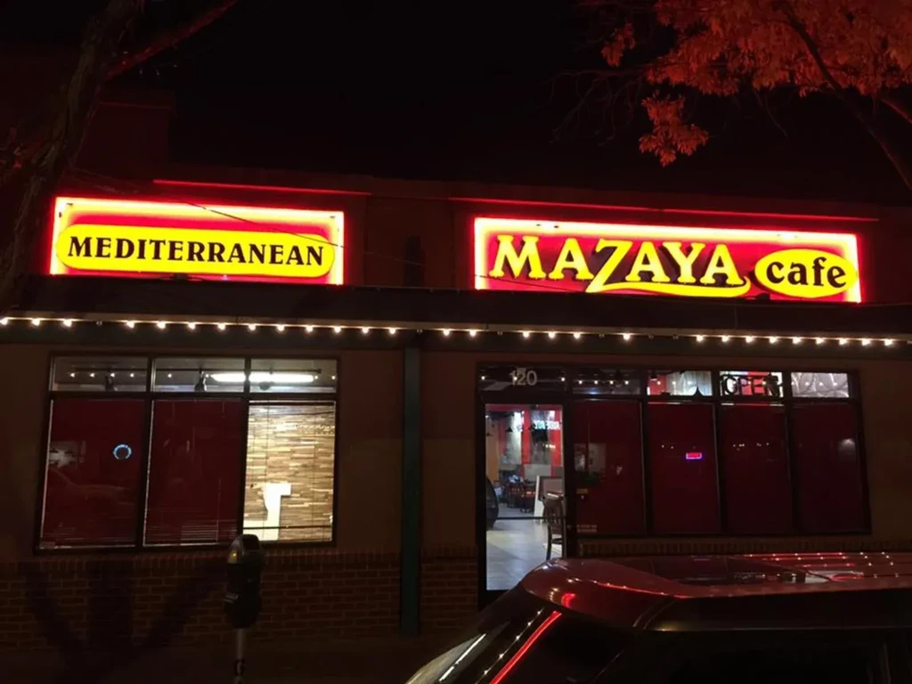 MAZAYA cafe storefront at night, illuminated by bright red neon signs.