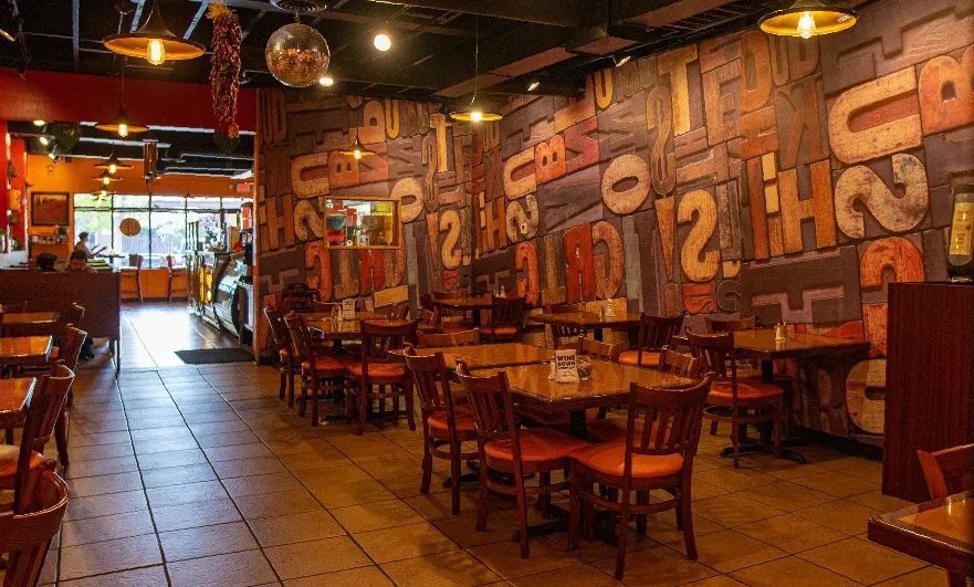 Casual restaurant interior with wooden tables, letterpress mural, and a disco ball.