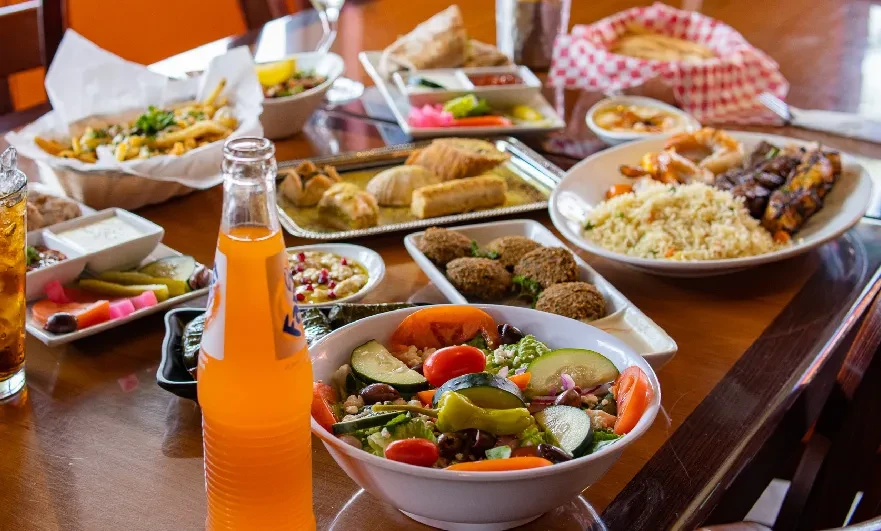 Table filled with Middle Eastern and Mediterranean dishes, drinks, and dips.