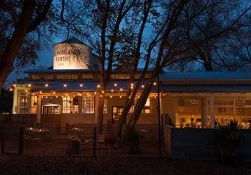Outdoor night view of 5 POINTS RANCH with silo and lit patio.