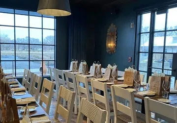 Set dining table in a rustic modern restaurant with large windows.