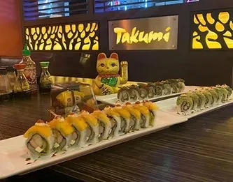 Long display of sushi rolls with Maneki-neko in Takumi restaurant.