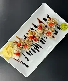 Eight sushi rolls with tomato, crunchy topping, sauce, ginger, and wasabi.