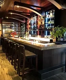 Sophisticated bar interior with illuminated bottle display and bar stools.