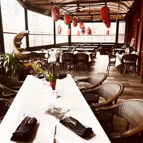 Empty, sepia-toned Japanese restaurant sunroom with red kanji lanterns.
