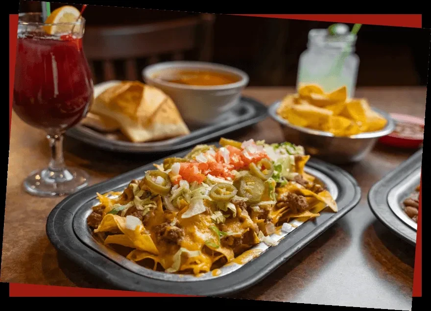 Large platter of cheesy nachos and other Tex-Mex food on a table.