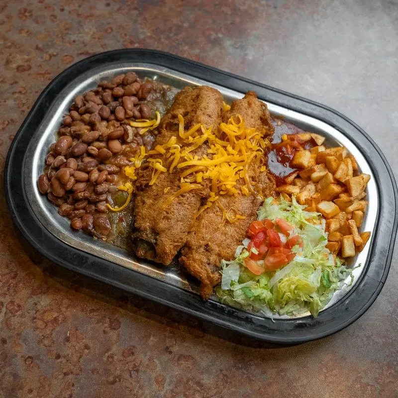 Two golden-brown chili rellenos, cheese, pinto beans, potatoes, and salad.