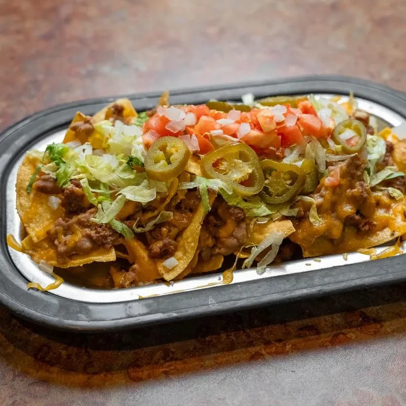 Generously topped nachos with melted cheese, meat, beans, and vegetables.
