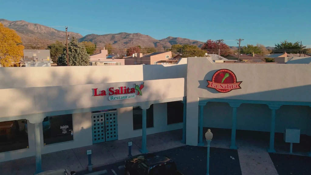 Adobe-style La Salita Restaurant exterior, logo, parking lot, mountains.