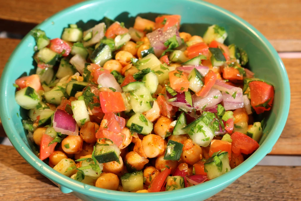 Chickpea salad with cucumber, tomato, onion, herbs in a teal bowl.