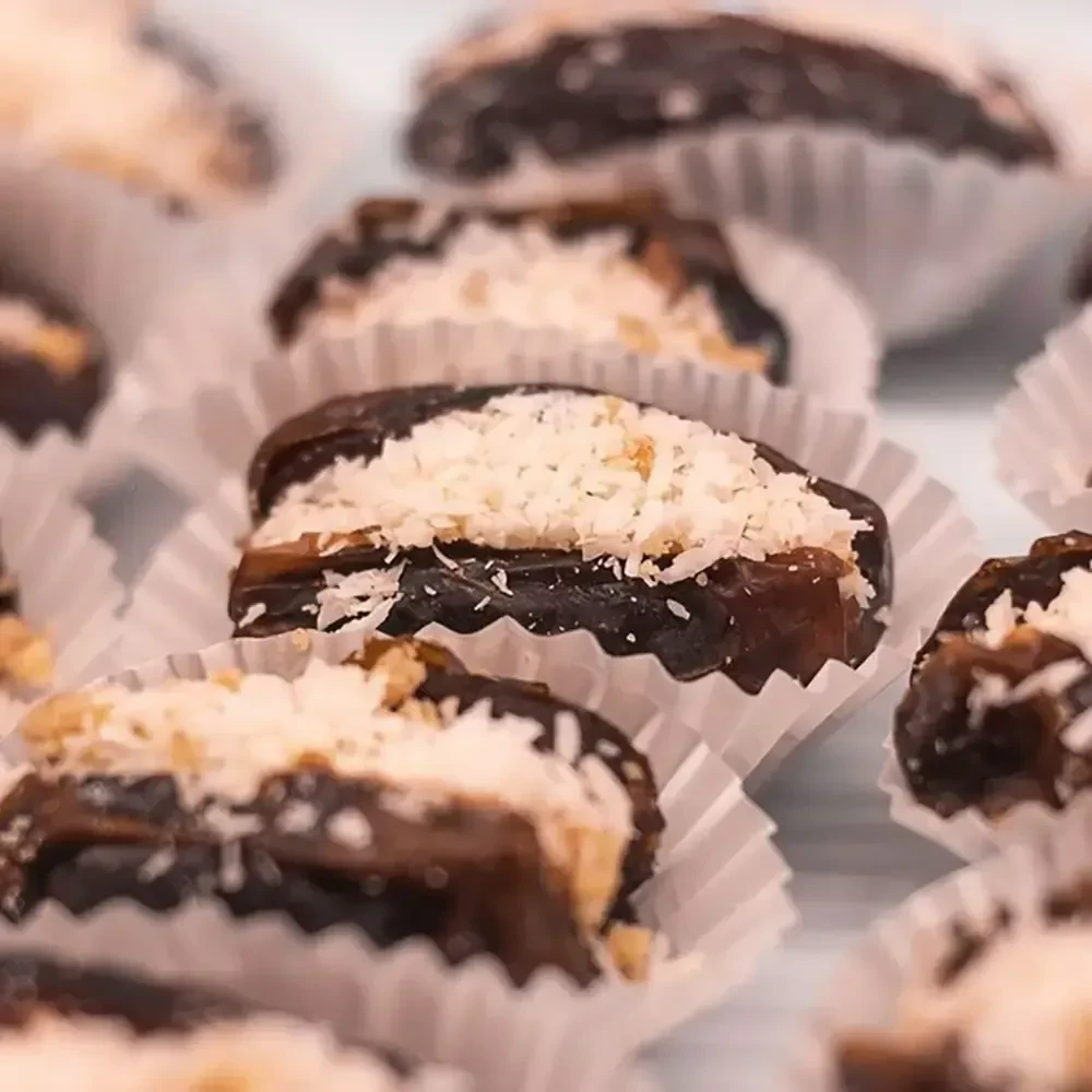 Stuffed dates in paper cups, topped with coconut flakes and nuts.