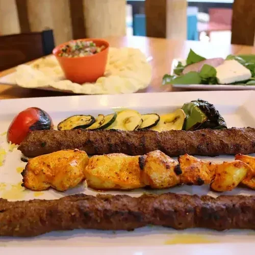 Grilled Middle Eastern meat kebabs, vegetables, and salad platter.