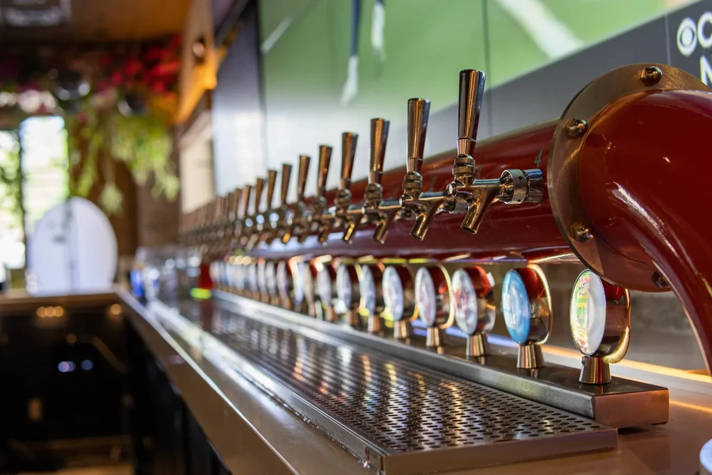 Modern bar with a long row of illuminated beer taps.