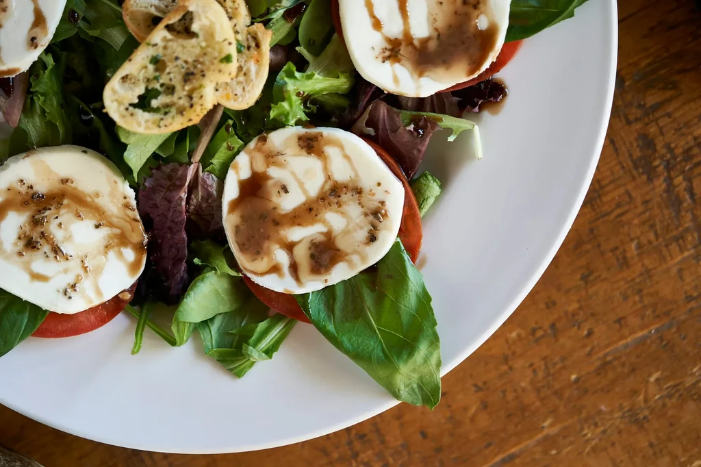 Close-up: Caprese-style salad with mozzarella, tomatoes, balsamic glaze, basil, and croutons.
