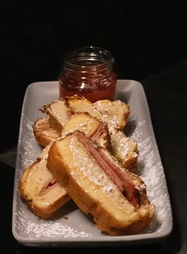 Fruit-filled sweet bread slices, powdered sugar-dusted, with a jar of jam.