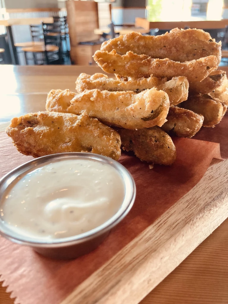 Golden-brown fried food with creamy dipping sauce on a rustic board.