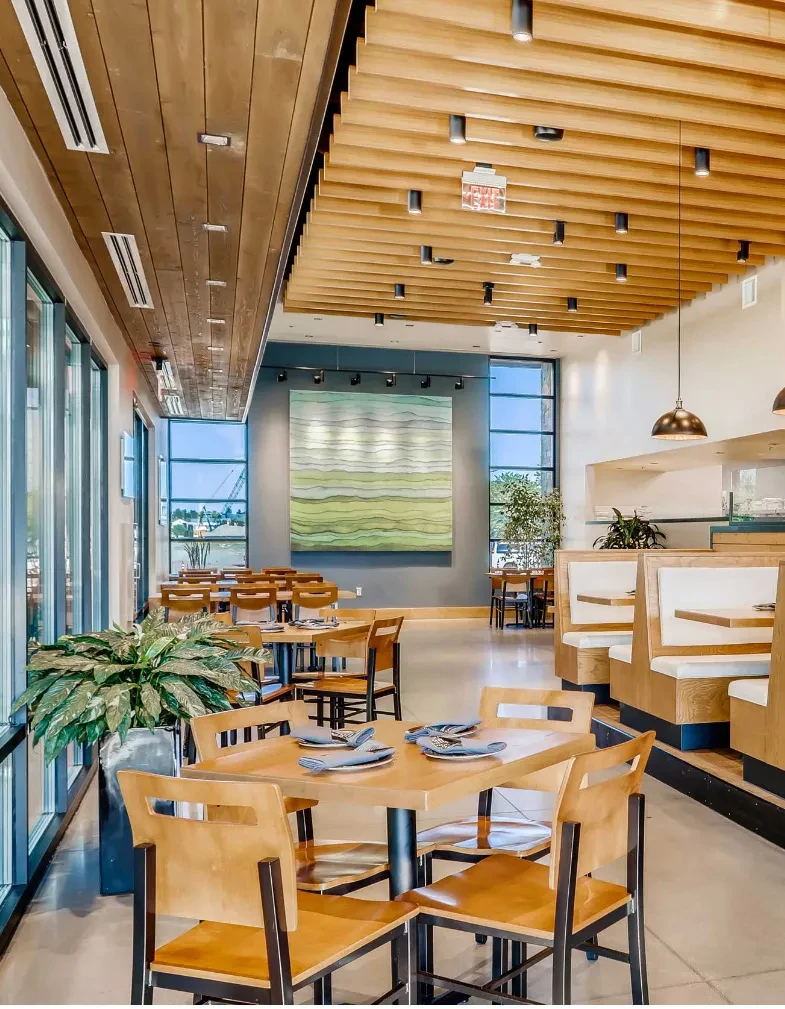 Modern, empty restaurant dining room with large windows and abstract art.