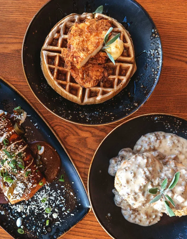 Three breakfast dishes: chicken and waffles, biscuits and gravy, savory items.