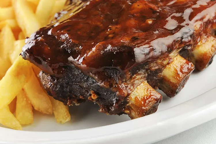 Barbecue ribs with thick sauce and a side of french fries.