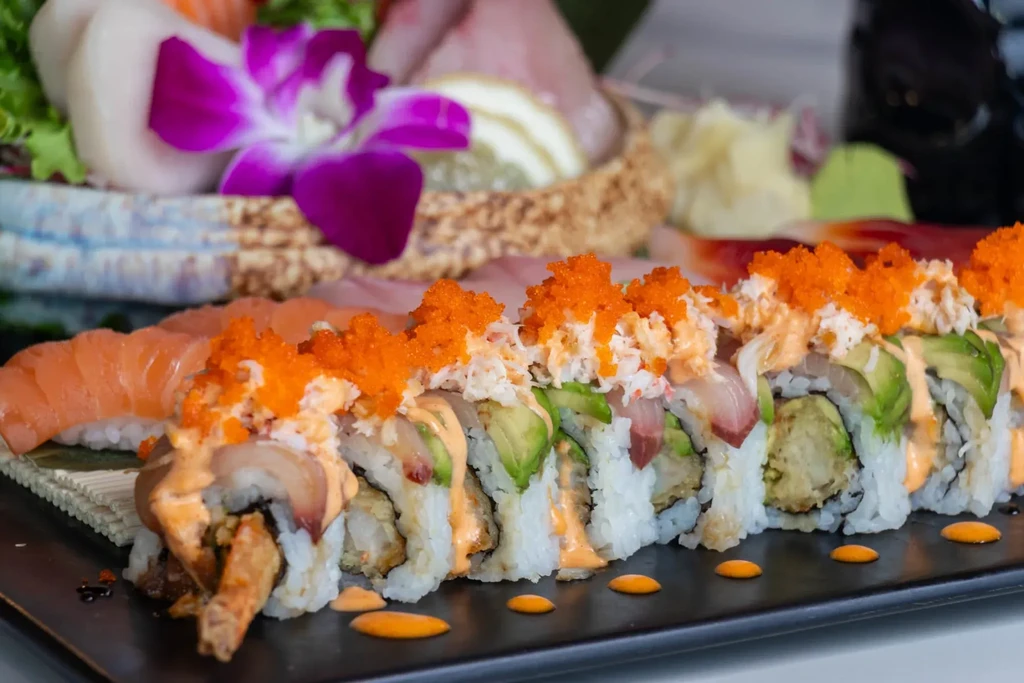 Vibrant sushi roll, salmon nigiri, and sashimi platter garnished with orchid.