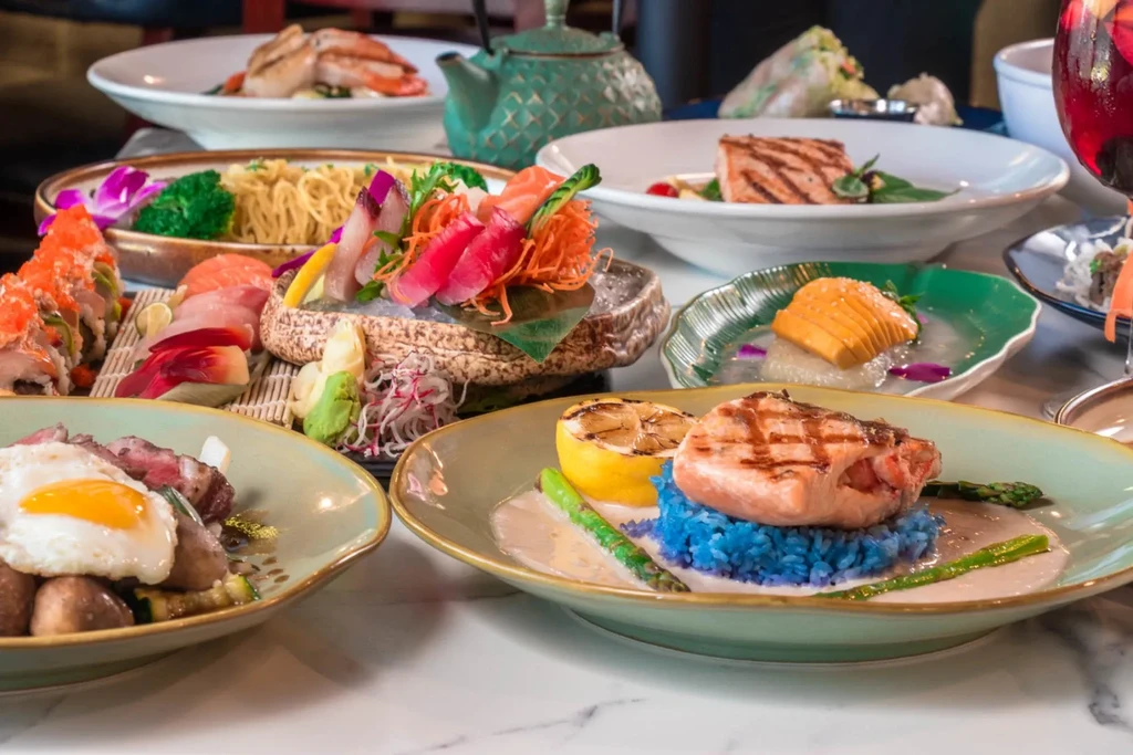 A lavish spread of beautifully plated Japanese and fusion cuisine on marble.