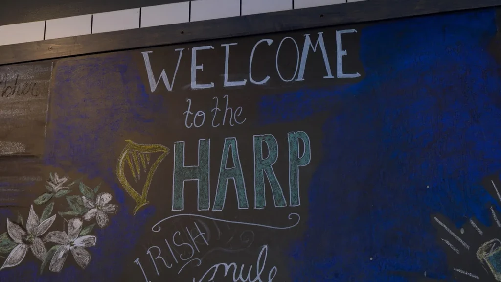 Hand-drawn chalk art sign: 'WELCOME to The Harp' and Irish mule.