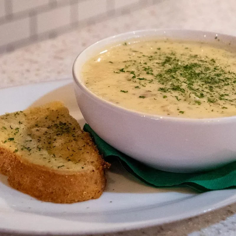Creamy soup with green herbs and a golden garlic bread slice.