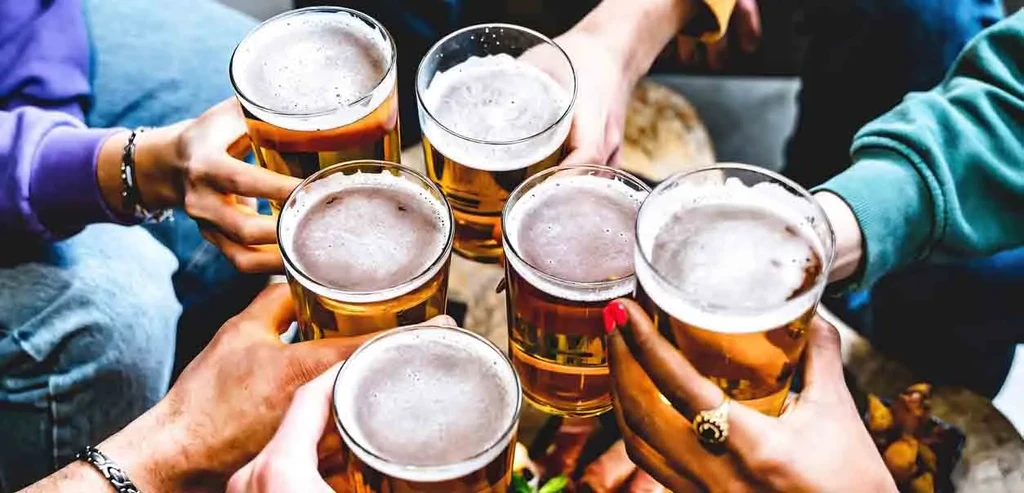 Multiple hands clinking beer glasses, celebrating together.