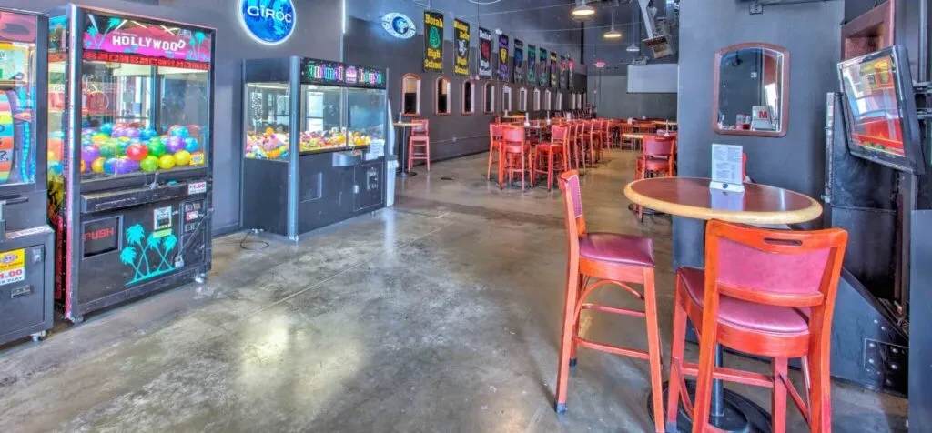 Dimly lit entertainment venue with claw machines and bar seating.