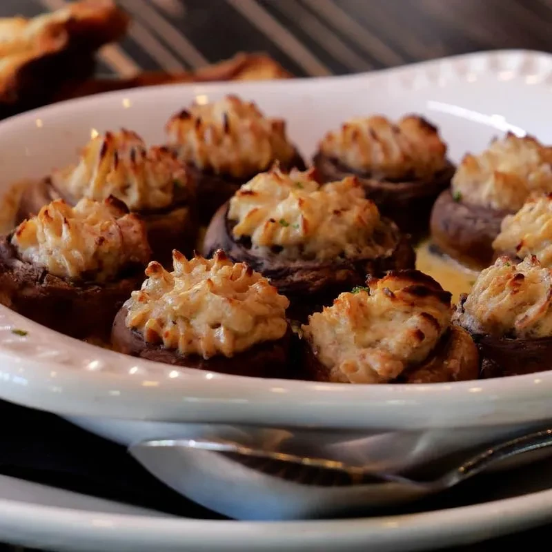Baked stuffed mushrooms with browned tops and green herbs.