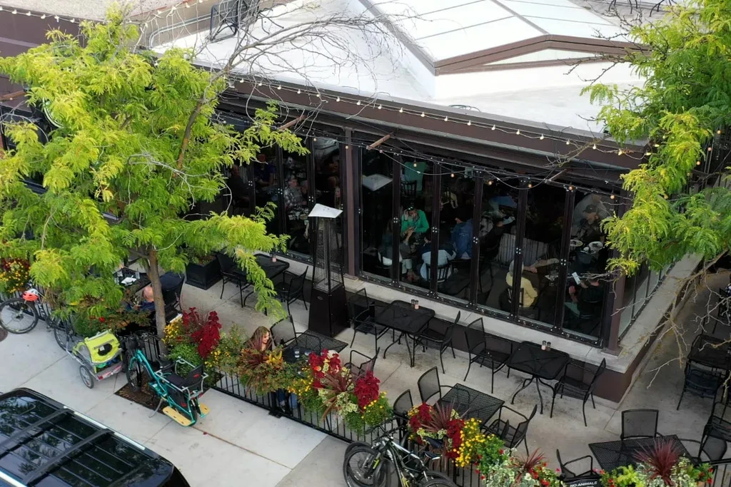 High-angle view of a busy urban restaurant with indoor and patio dining.